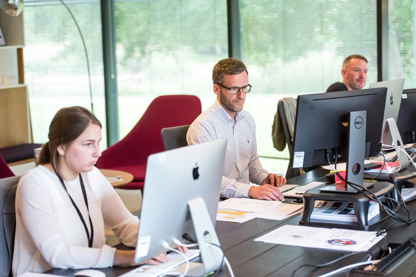 Three office workers using computers in a modern workspace
