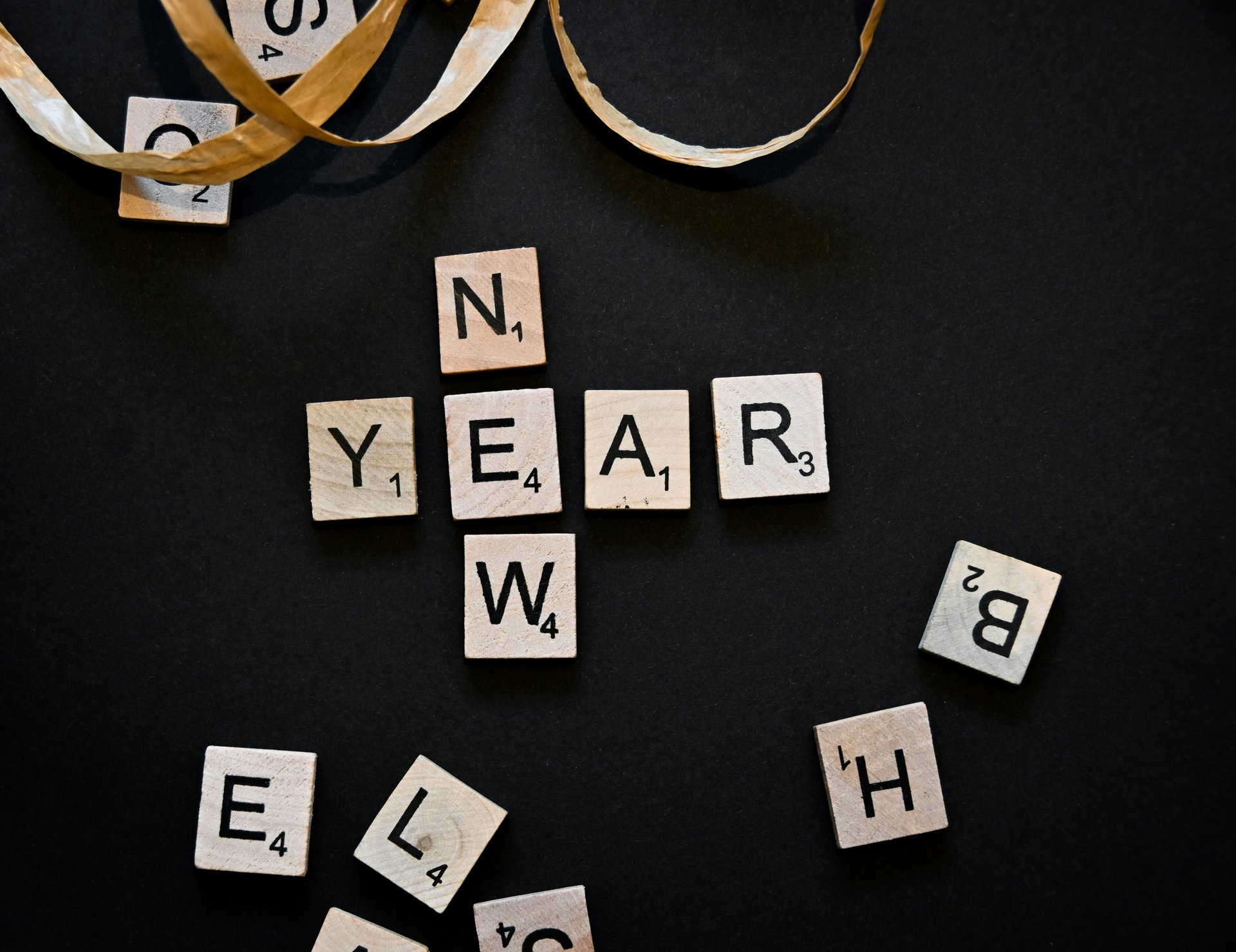 Wooden scrabble tiles spelling YEAR on dark surface